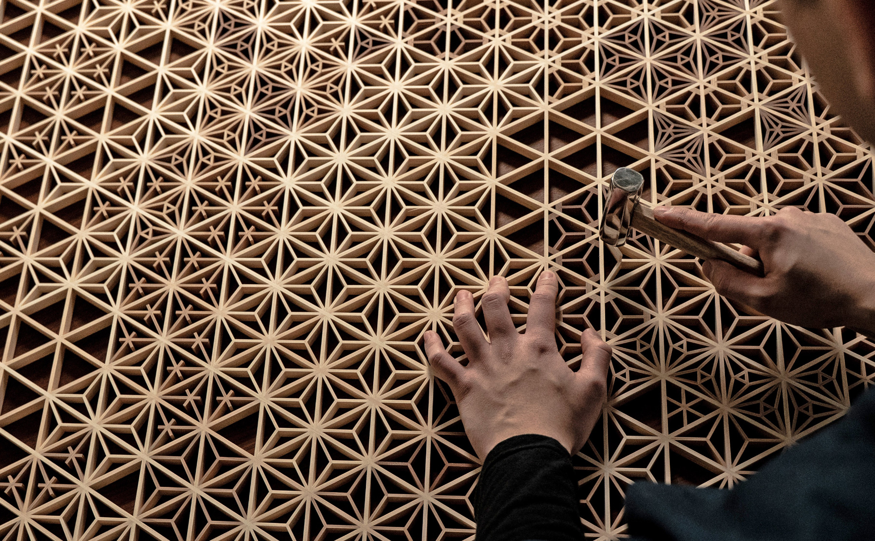 A Japanese craftsman carefully finishing a piece of traditional kumiko woodworking