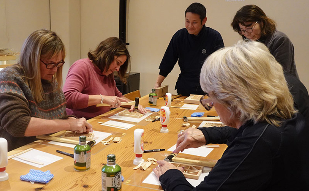 Participants creating kumiko pieces while listening to guidance from an instructor